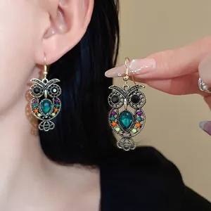 Vintage hollow owl drop earrings with vibrant rhinestones and emerald-colored center stone.