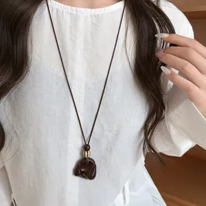 Close-up of vintage wooden pendant necklace on white blouse for an elegant casual look.