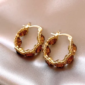 Detailed view of luxury gold-plated hoop earrings with faceted amber rhinestones inlay.