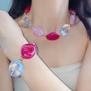 Dettaglio di un set di gioielli in acrilico con perline marmorizzate rosa su modella