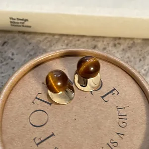 Close-up of retro Maillard style resin stud earrings with gold finish and cat-eye luster