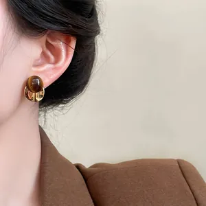 Close-up of vintage Maillard resin stud earrings with gold metallic base on model's ear