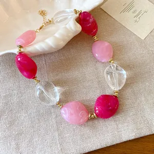 Primo piano di una collana di perle acriliche marmorizzate rosa e trasparenti stile dolce.