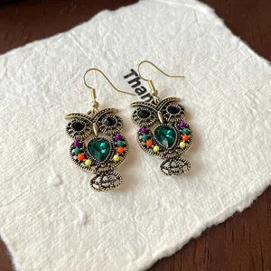 Detailed macro view of vintage owl earrings featuring green teardrop gemstone and colorful beads
