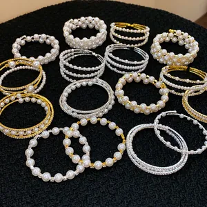 Exquisite Kollektion von Perl- und Strass-Doppelarmbändern auf schwarzem Hintergrund.