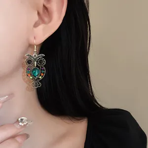 Vintage gold owl drop earrings with emerald teardrop rhinestone shown on model