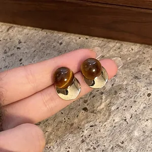 Close-up of retro Maillard style resin stud earrings with gold metal disc detail