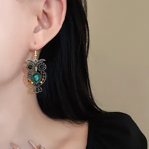 Detailed close-up of a vintage hollow owl earring with colorful rhinestones and green gem