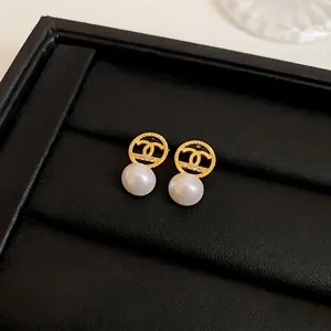 Elegant French style gold round stud earrings with white pearl and crystal accents on black