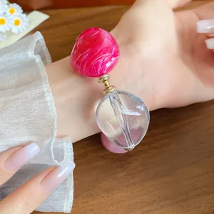 Dettaglio ravvicinato di un orecchino in acrilico marmorizzato rosa e goccia trasparente