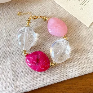 Dettaglio di un braccialetto di perle acriliche marmorizzate rosa e trasparenti