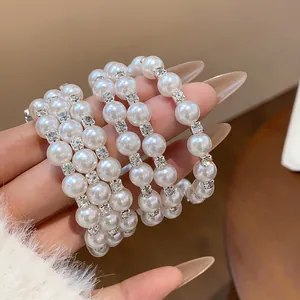 Makrodetail des eleganten mehrlagigen Perlenarmbands mit funkelnden Strass-Abstandhaltern