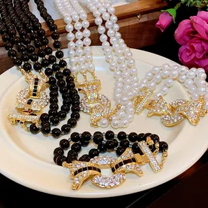 Dettaglio di lussuosa collana di perle multifilo con chiusure dorate e strass incastonati.