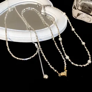 Gedetailleerd overzicht van een zilveren kralenketting met parels en gouden hartvormige hanger.
