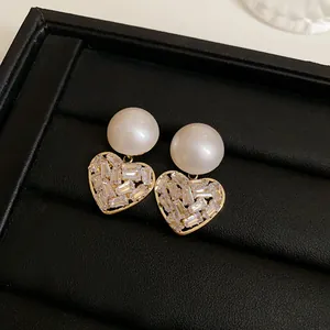 Detailed close-up of French style gold heart earrings with pearls and crystals