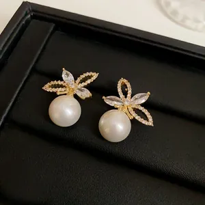 Detailed macro view of French luxury pearl earrings with crystal butterfly motif
