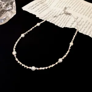 Detailweergave van een minimalistische ketting met kleine witte parels en zilveren kralen