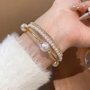 Detaillierte Makroansicht eines eleganten zweilagigen Perlenarmbands mit Strass am Handgelenk.