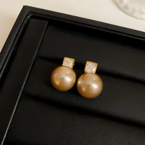 Close-up detail of vintage French style golden pearl earrings with square zircon studs