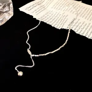 Close-up van zilveren minimalistische ketting met kubuskralen en bolvormige hanger
