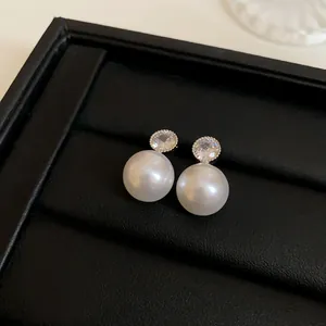 Macro view of elegant white pearl earrings with zircon tops on a black jewelry display