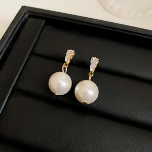 Close-up of vintage gold pearl earrings with sparkling rectangular stones on black box
