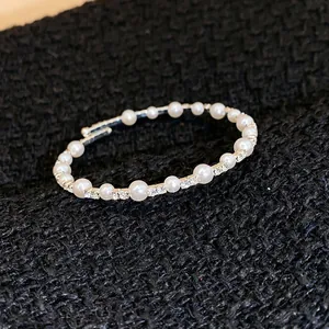 Detail eines eleganten offenen Armreifs mit glänzenden Perlen und funkelnden Straßsteinen