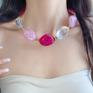 Primo piano di una collana in acrilico colorata con perle ovali rosa e trasparenti.