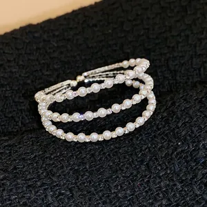Nahaufnahme eines eleganten mehrlagigen Armbands mit weißen Perlen und glitzernden Steinen