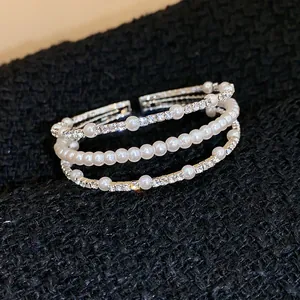Detailansicht eines mehrlagigen Armreifs mit eleganten weißen Perlen und glänzenden Kristallen