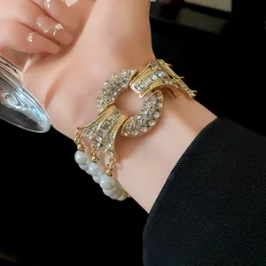 Vista dettagliata di un bracciale di lusso francese con diamanti e perle al polso di una modella.