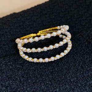 Detailansicht eines eleganten mehrlagigen offenen Armbands mit Perlen und Strass auf schwarzem Stoff