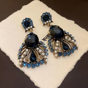 Vintage blue oval gemstone and pearl drop earrings with ornate gold-tone frame.