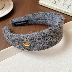 Close-up of a gray flocked wide headband featuring a gold Korea badge and fuzzy texture