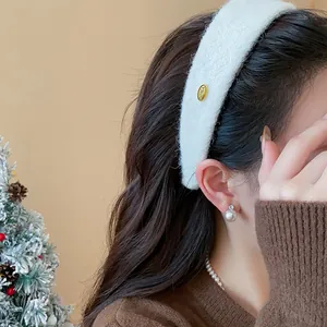 Detail of white flocked wide headband featuring a small gold KOREA logo tag.