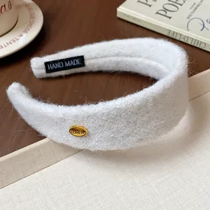 Close-up of a white flocked wide headband with golden KOREA badge