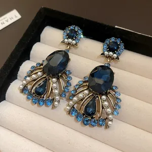 Detailed view of vintage drop earrings featuring dark blue crystals and elegant white pearls