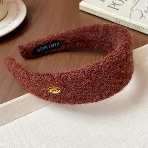 Detailed close-up of a reddish-brown bouclé textured wide headband with a gold Korea tag