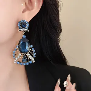 Close-up of vintage statement earrings with blue crystals and pearls worn on ear