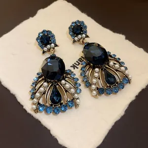 Ornate vintage teardrop earrings with deep blue crystals and pearls on textured card.