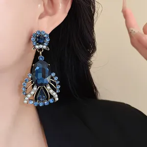 Close-up of vintage oversized blue rhinestone and pearl drop earrings on model's ear