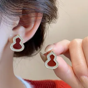 Detailed view of red hulu gourd earrings with sparkling zirconia on an Asian model
