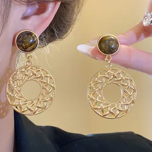 Elegant gold-toned earrings featuring tiger eye stone and intricate hollow circular design