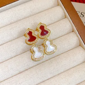 Detailed view of red and white gourd-shaped stud earrings with sparkling zircon borders