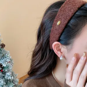 Detail shot of a stylish brown flocked wide headband featuring a gold metal tag