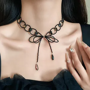 Dettaglio di girocollo nero minimalista con pendente a fiocco e perle geometriche