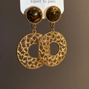 Close-up of vintage gold earrings with tiger eye stones and hollow circular pendants