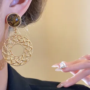 Detail shot of vintage hollow woven earrings with tiger eye stone and gold-tone finish.