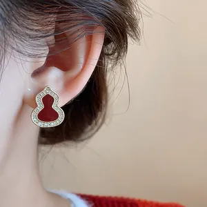 Close-up of red enamel gourd earring with pavé zircon border on ear