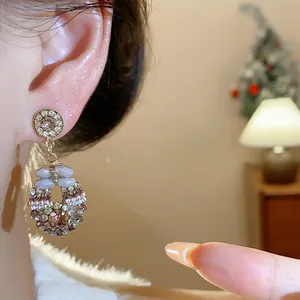 Close-up of elegant rhinestone pendant earring worn on ear with warm background